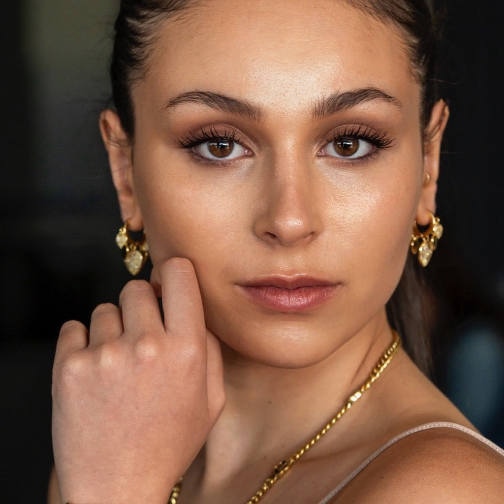 Heart Charm Huggie Earrings in gold with cubic zirconias on model