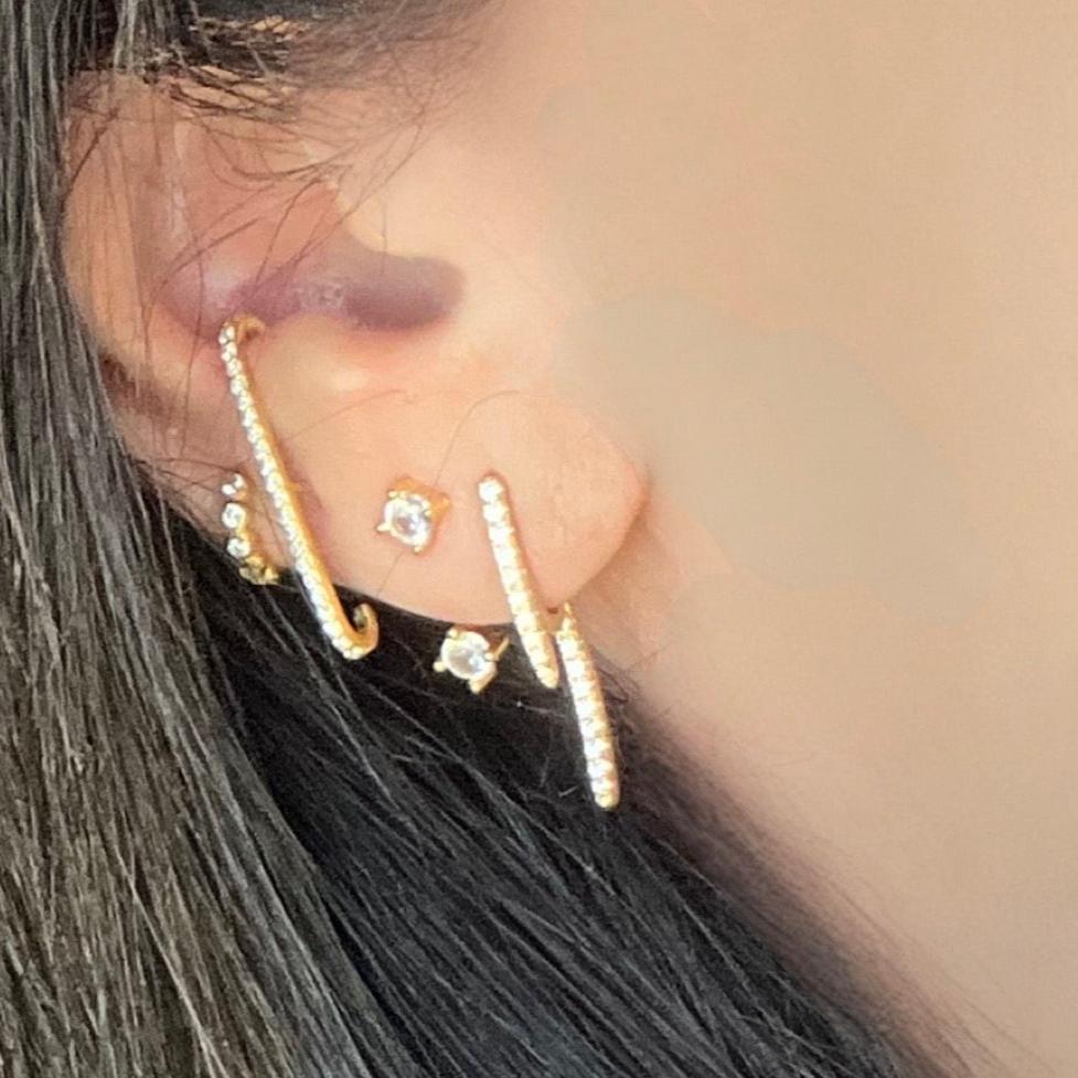 single ear wrap stud earring shown on stack  of earrings in ear