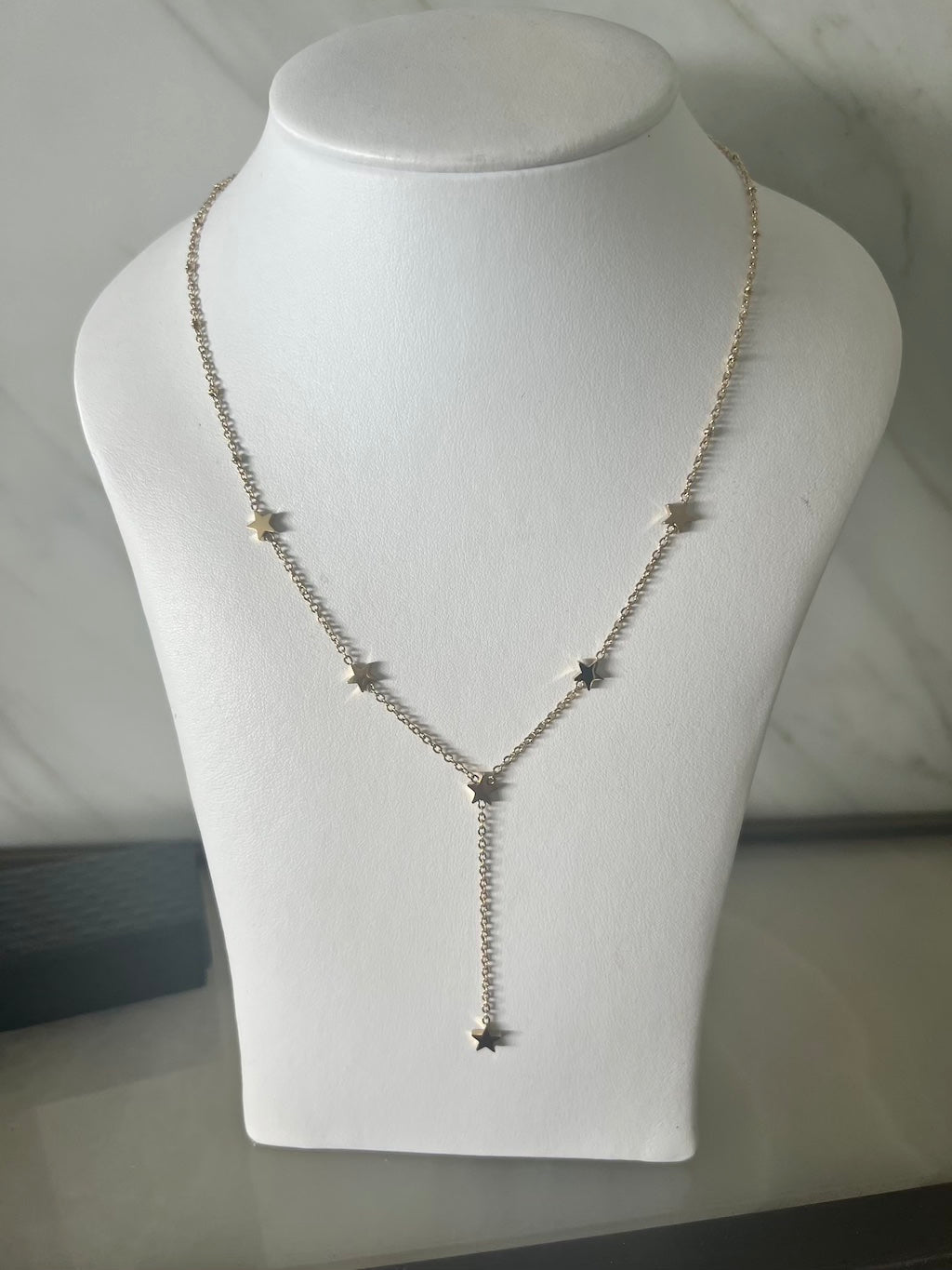 gold lariate necklace with gold star charms on mannequin