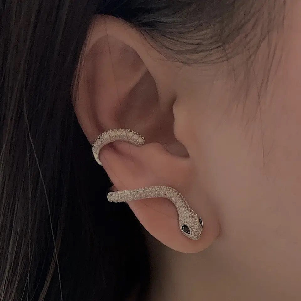 silver snake cuff earring with cubic zirconias and green eyes. sold as a single earring
