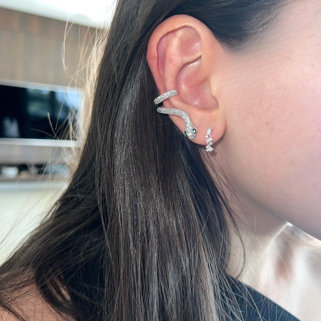silver snake cuff earring with cubic zirconias and green eyes. sold as a single earring 